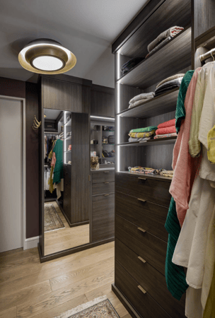 brown walkin custom closet with hanging shelving, mirrored doors, LED lighting and drawers