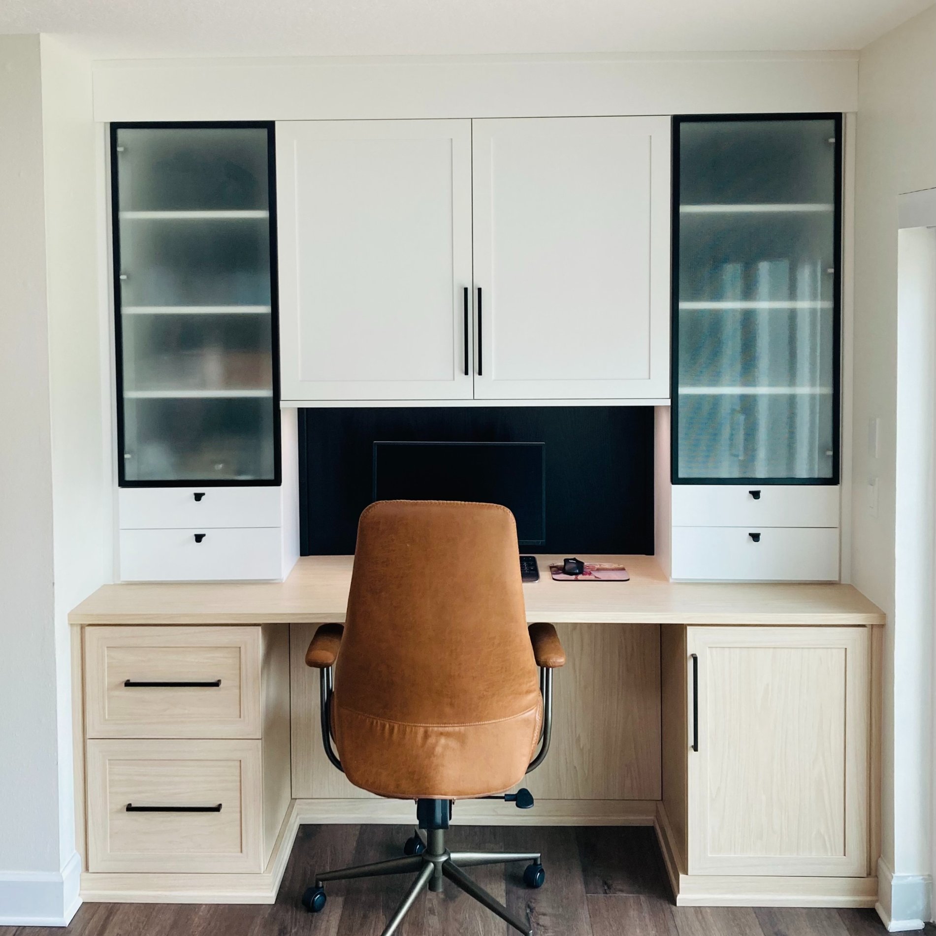 A modern home office styled in dove and natural wood tones with sleek black hardware accents.