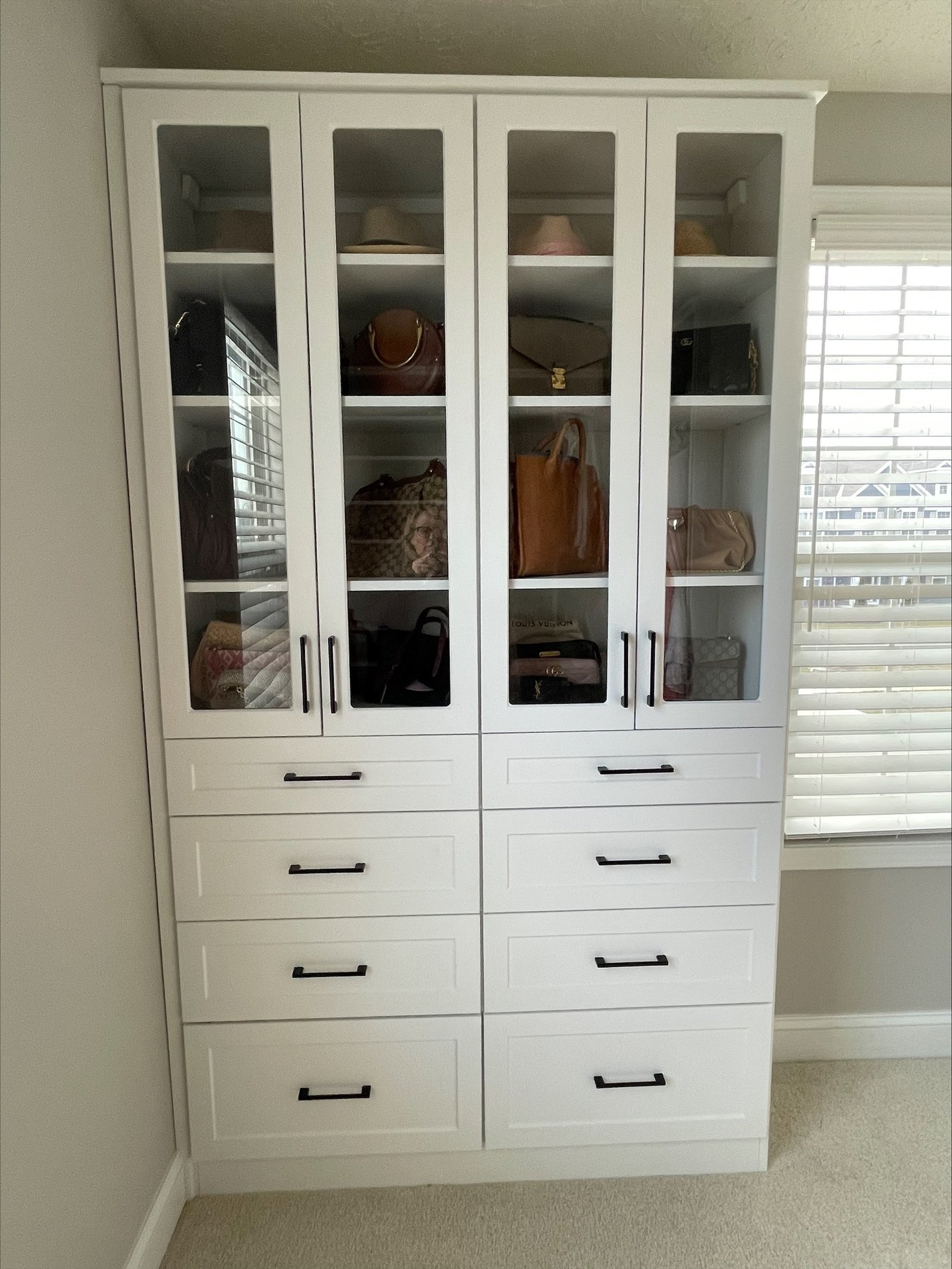 Custom closet storage with glass cabinetry to highlight purses and accessories.