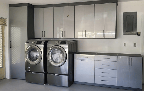 Custom garage organization and laundry room storage with glossy white and charcoal cabinets, built-in washer and dryer, and modern utility storage designed by California Closets in South Florida near Boca Raton.