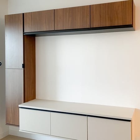 Floating media centre with lower cabinetry in an off white finish, side cabinetry, and upper cabinets in a contrasting wood grain finish.