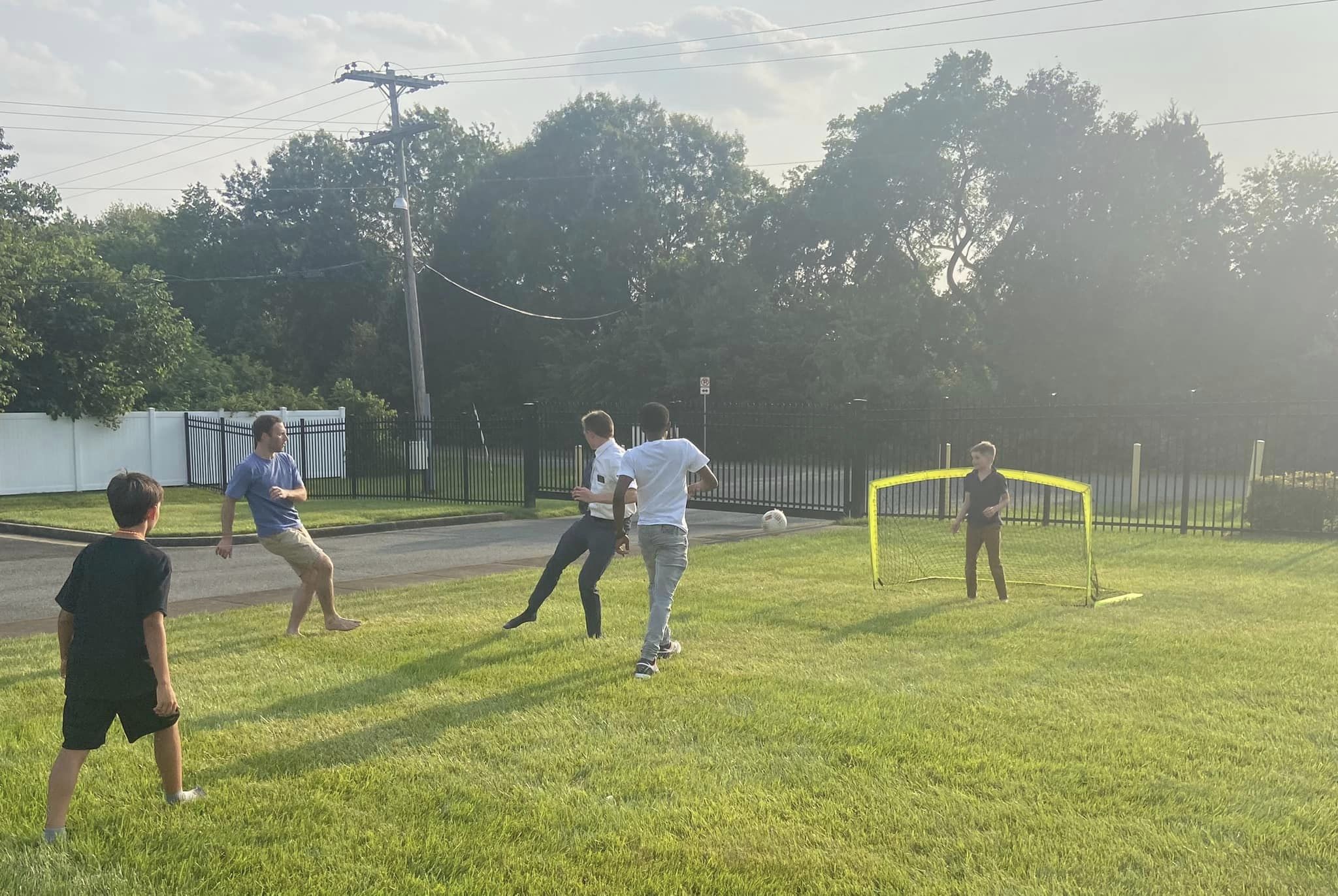 Group plays soccer at summer party on the front lawn of the church building.