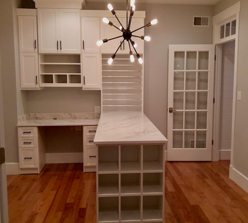 Custom craft room storage with a desk, shelving, and cabinets
