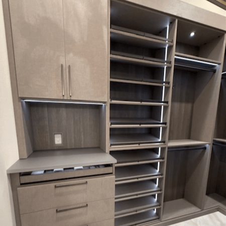 Primary closet in Corsican Weave with Ash backing, featuring full overlay cabinetry, Titanium Chroma surfaces, Everstyle accessory drawer, graphite finishes, slanted shoe shelving, and integrated lighting throughout.
