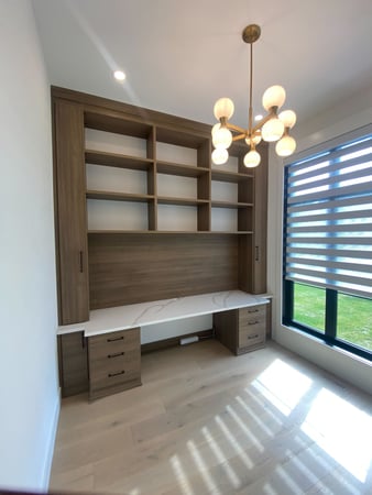 California Closets home office in a mid-tone wood grain finish and a contrasting white countertop.