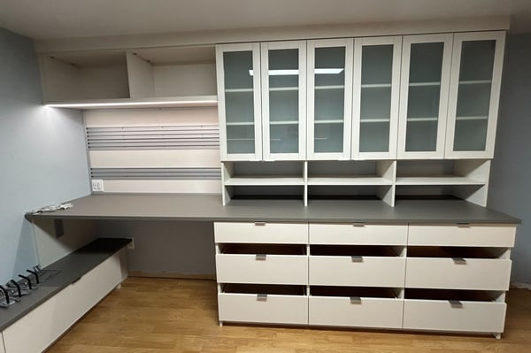 custom home office with drawers, glass cabinet doors and a slot wall