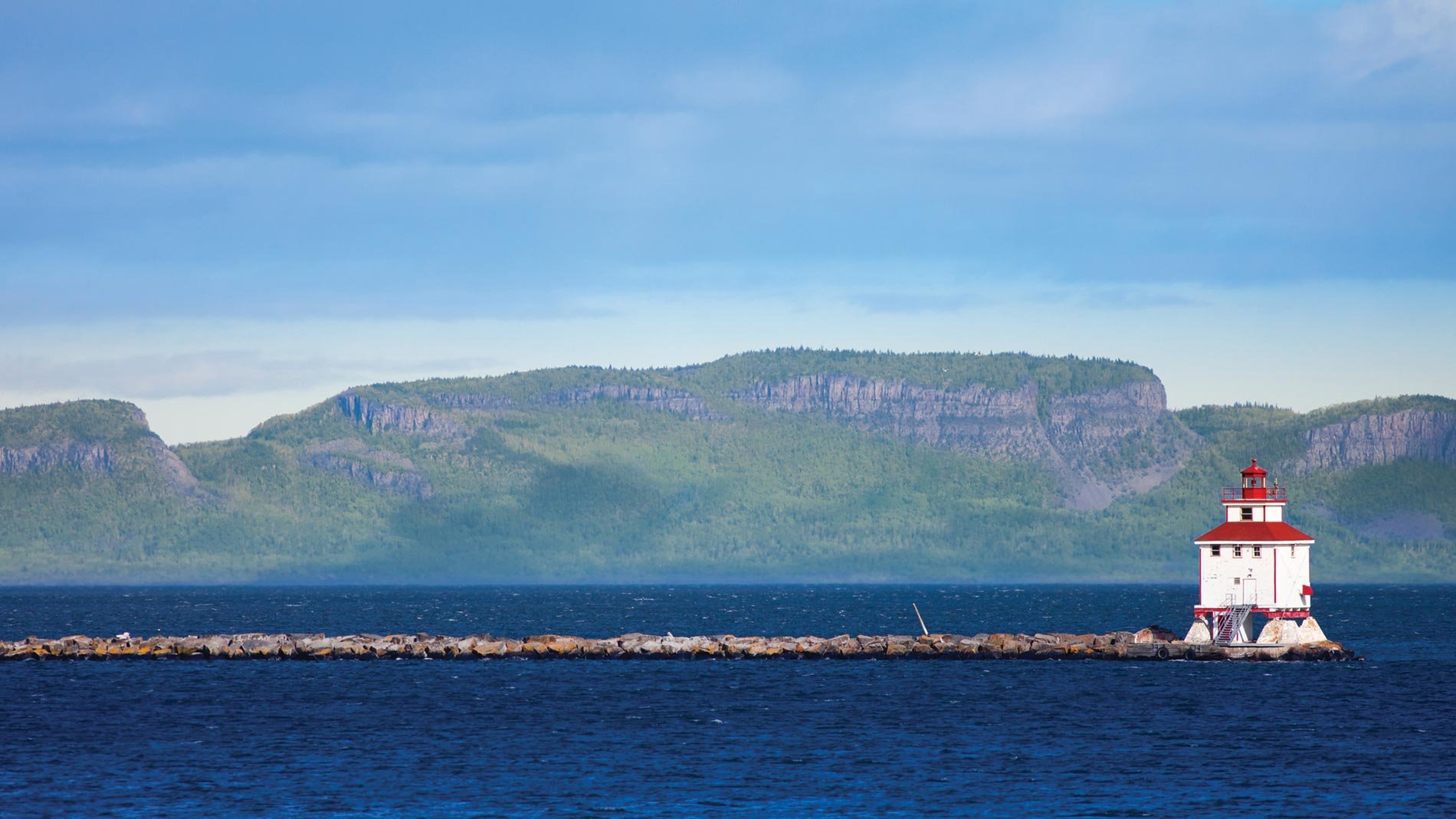 Vue d'un phare et d'une formation rocheuse en arrière-plan, photographiés depuis un lac