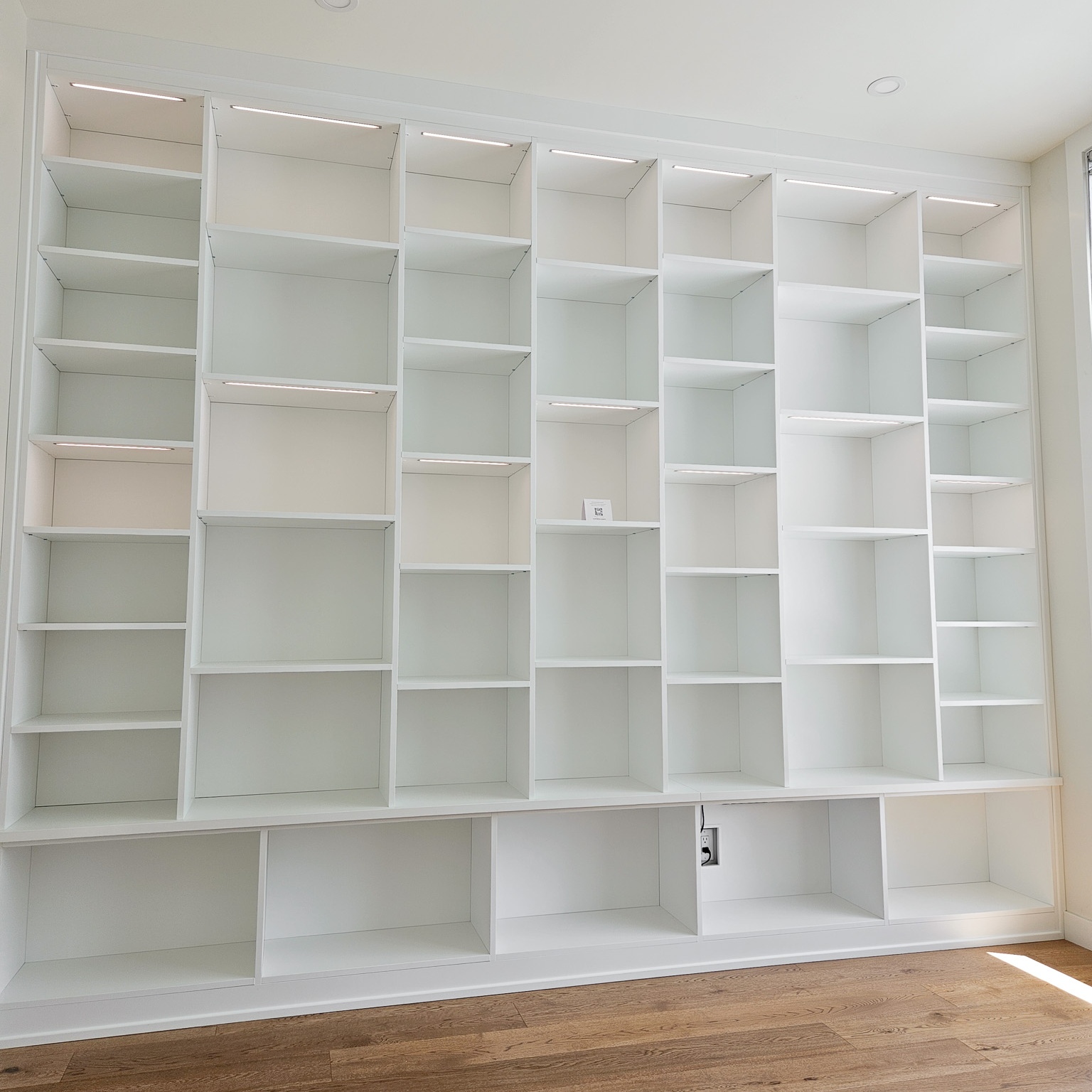 Wall to wall and floor to ceiling bookshelves. An all white system with thoughtfully placed lighting.