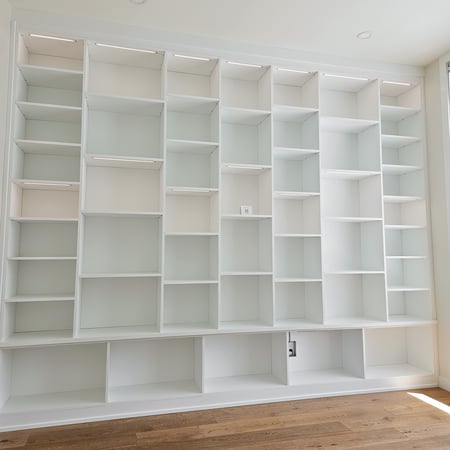 Wall to wall and floor to ceiling bookshelves. An all white system with thoughtfully placed lighting.