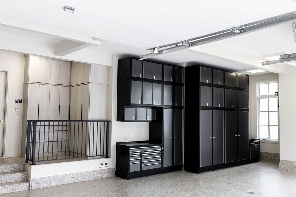 Custom garage with black and gray metal cabinets and floor to ceiling storage in a light wood grain finish.