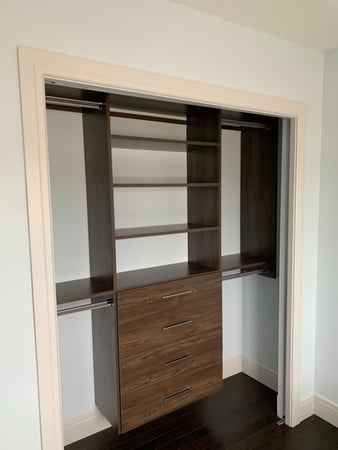 Simple wall suspended reach-in closet with a combination of double hang, shelving, and drawers. Designed in a dark wood grain finish.