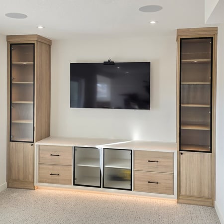Media centre with lower middle storage, tower storage on both sides, toe kick lighting, and reeded glass.