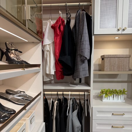Walk in closet with shoe storage and cabinets.