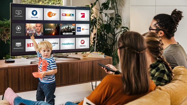 Customers of Deutsche Telekom watch television on their Smart TV while a child points at a section of the screen.