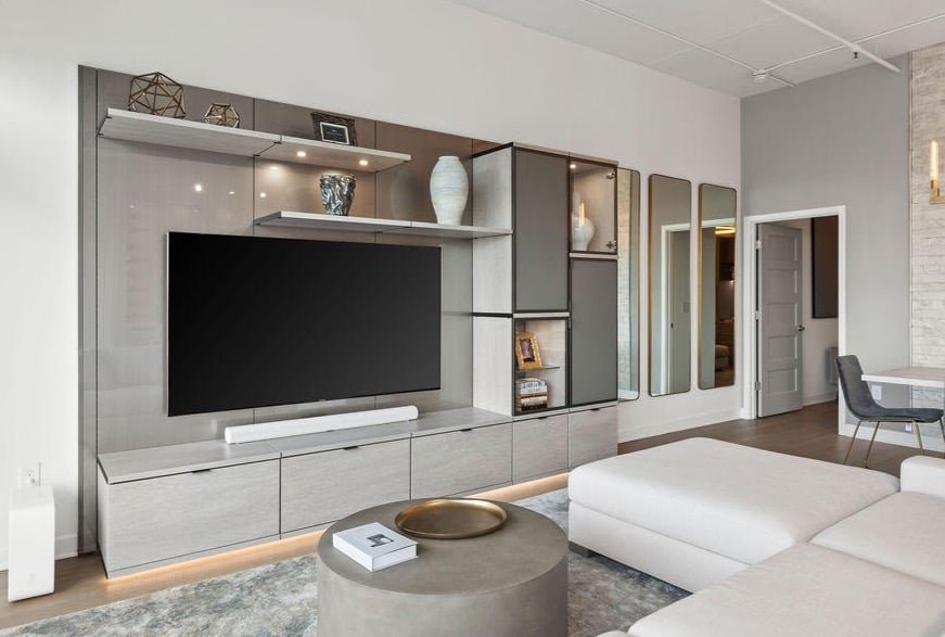 Earth tone media center in living room, with beige couch, chandelier, and mirrors
