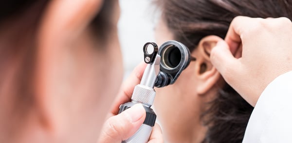Audiologist uses an otoscope to check for fluid in his patient's ear.