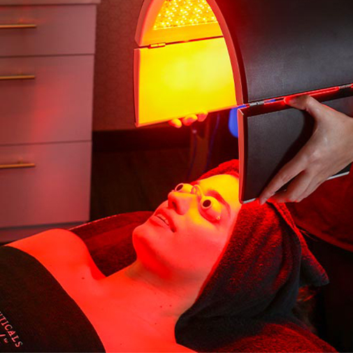 Patient receiving SkinSmooth treatment with LED red light tool.