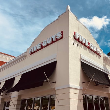 Exterior photograph of the entrance to the Five Guys restaurant at 1707 Northwest Saint Lucie W Boulevard in Port Saint Lucie, Florida.