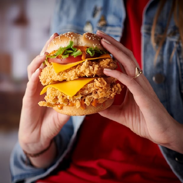 Person holding a KFC Double Crunch Burger with two hands