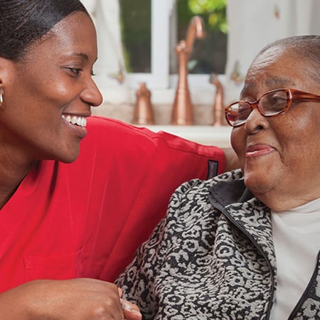 A Bayada Health care employee smiles with an elderly woman.