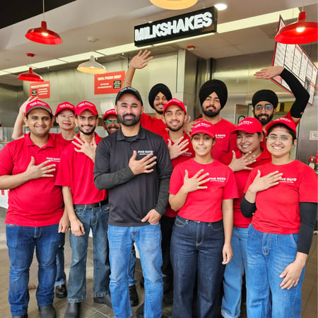 Crew members pose for a photograph in front of the kitchen at the Five Guys restaurant in Markham, Ontario, Canada.