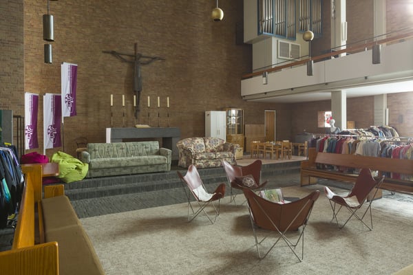 Innenbereich der zum Sozialkaufhaus umgestalteten Heilig-Geist-Kirche. Sitzgelegenheiten und Kleiderständer mit Altarbereich.