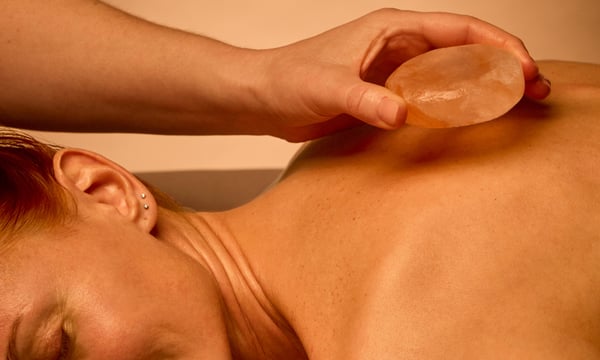 woman laying face down receiving a hot stone massage