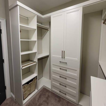A spacious white walk-in closet with built-in shelving and hanging rods.