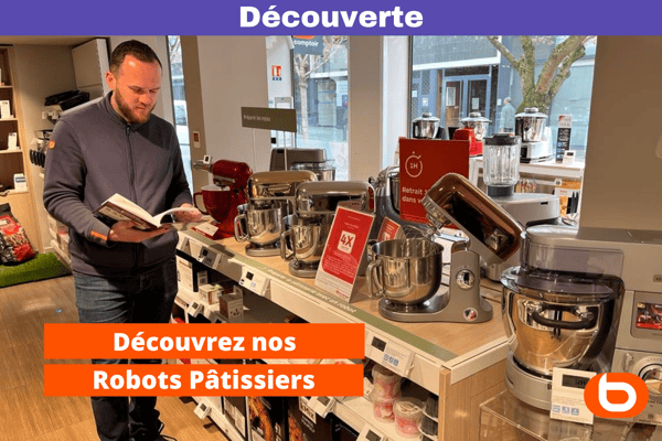 Un collaborateur lie un livre de cuisine dans le rayon des robots cuisiniers