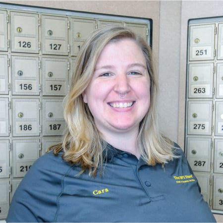 Smiling female associate standing in front of mailboxes at The UPS Store