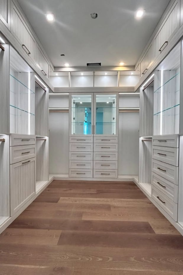 Walk-in closet with integrated strip lighting and modern glass shelving.