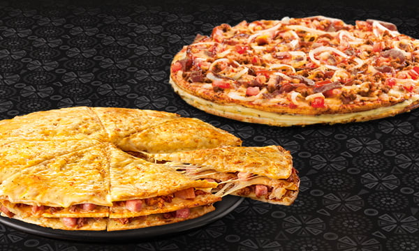Two large pizzas on a grill placed on a wooden table
