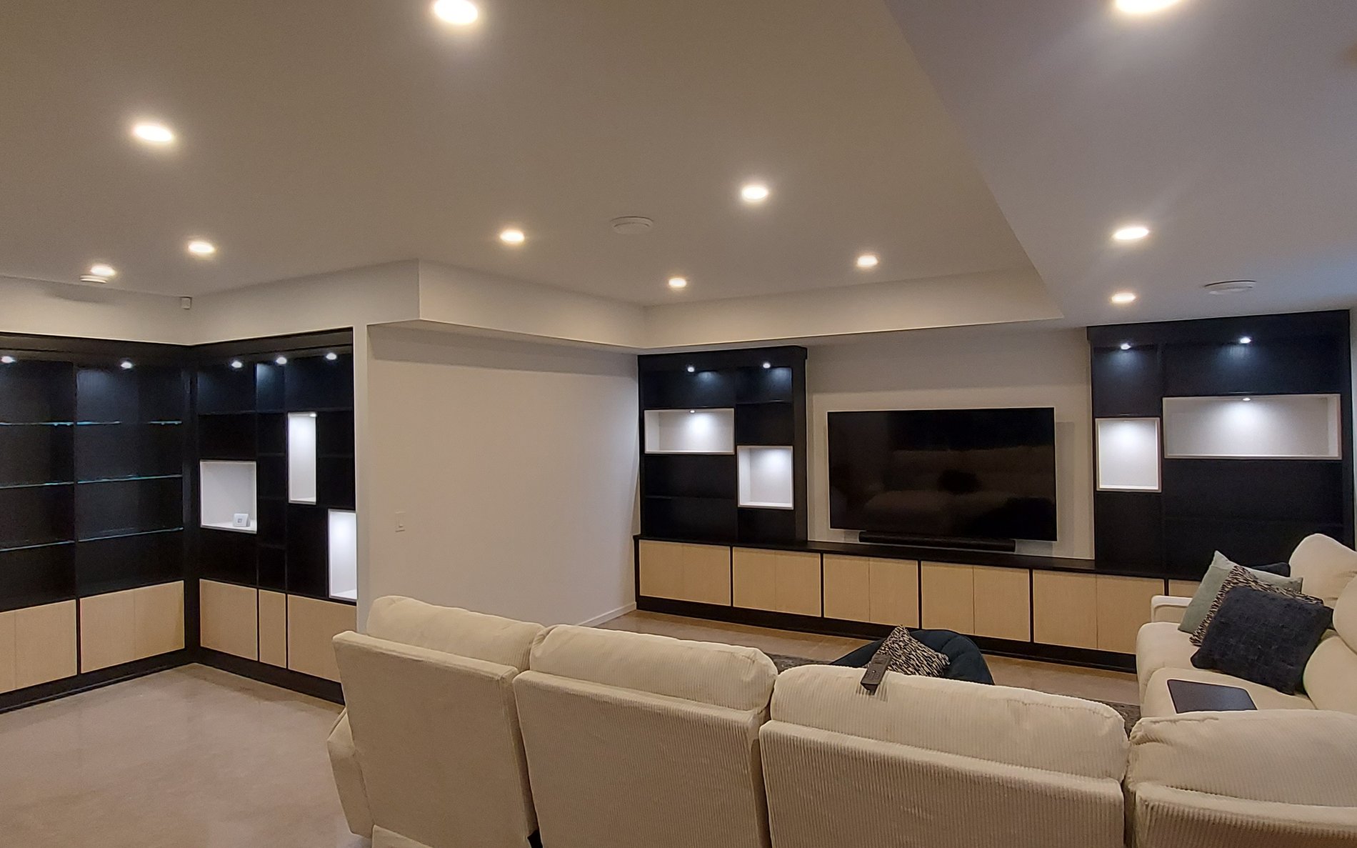 Black and natural media centre with lighting, open cubbies, glass shelves, and closed storage.
