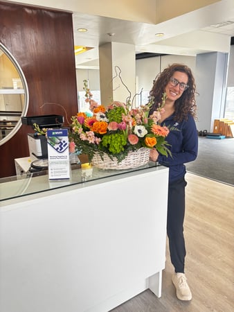 MVPT - Buffalo, NY Grand Opening 2026 Florianna PT, DPT at front desk area with flowers.