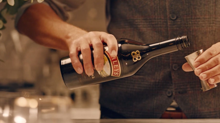 Person pouring Baileys Irish cream into cocktail shaker