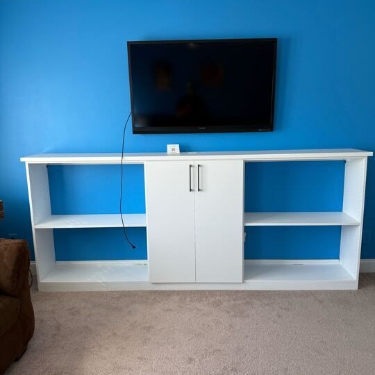 Greensboro - Custom closets - wall-mounted TV above a custom white media cabinet with open shelving and closed storage against a blue accent wall