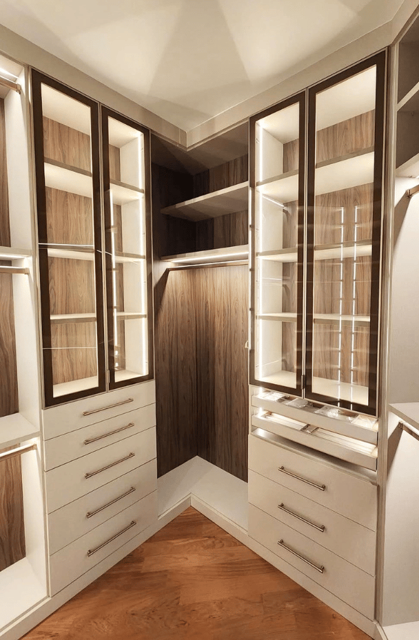 Custom luxury walk-in closet with integrated LED lighting, glass-front display cabinets, custom jewelry drawers, shoe storage, and rich dark wood finishes by California Closets in South Palm Beach near Boca Raton, Florida, designed for high-end modern home organization and boutique-style dressing room storage.