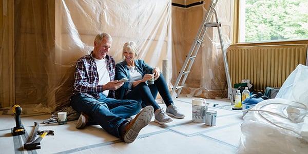 A man and woman sitting on the floor of a home renovation project.