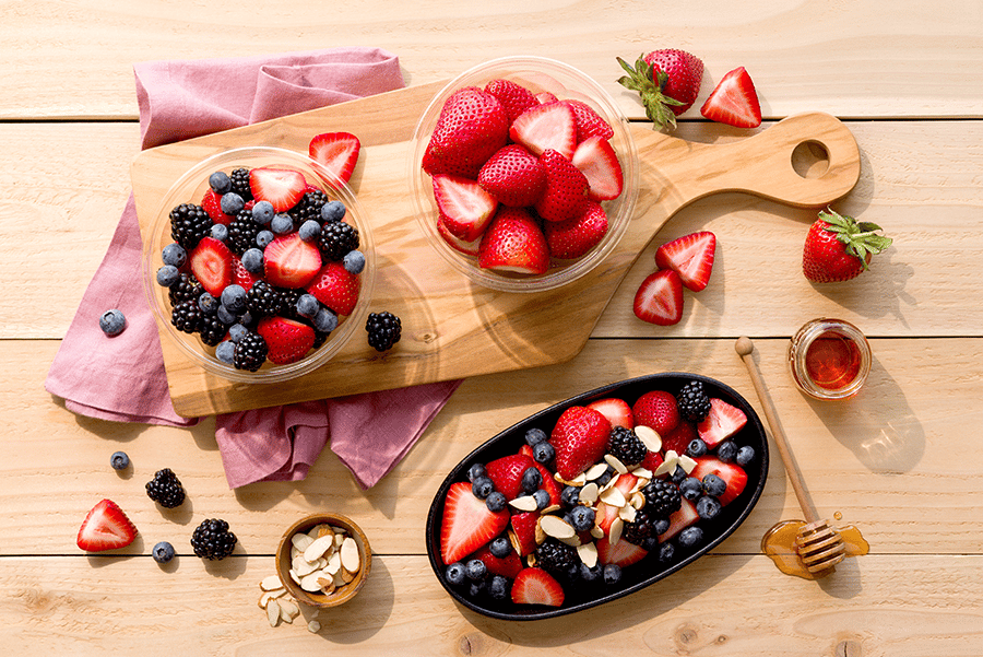 strawberries blueberries and granola on a cutting board