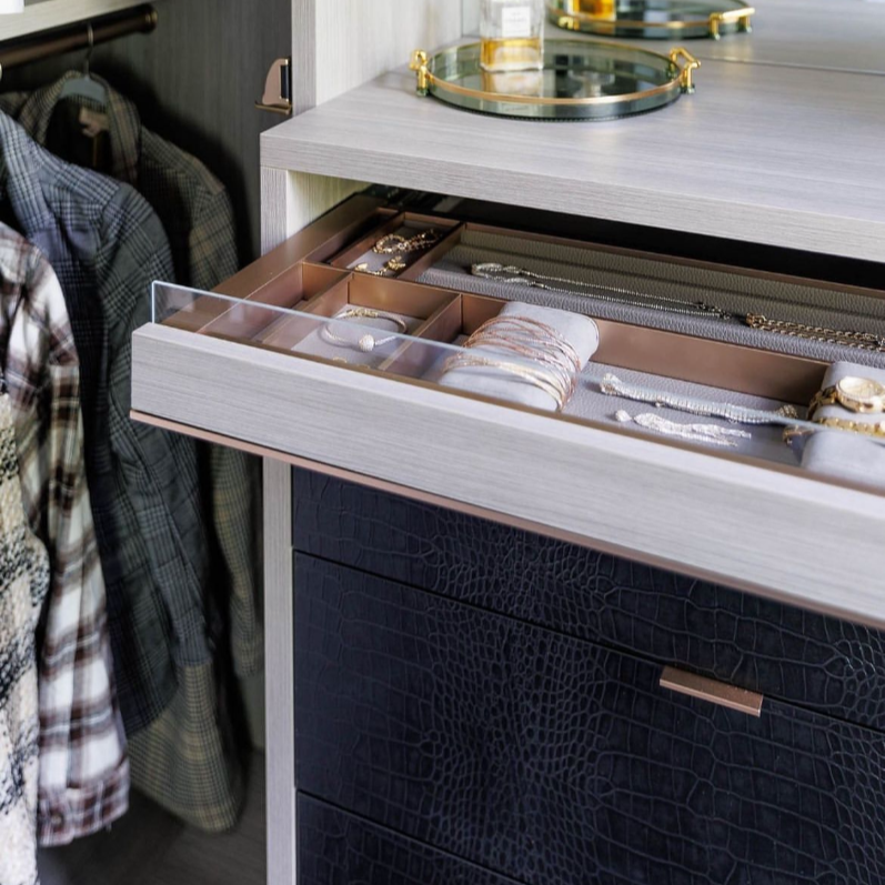 Everstyle accessory drawer with organized compartments above custom leather-front drawers in a luxury closet.