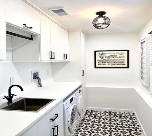 Custom laundry room with white cabinets and sink