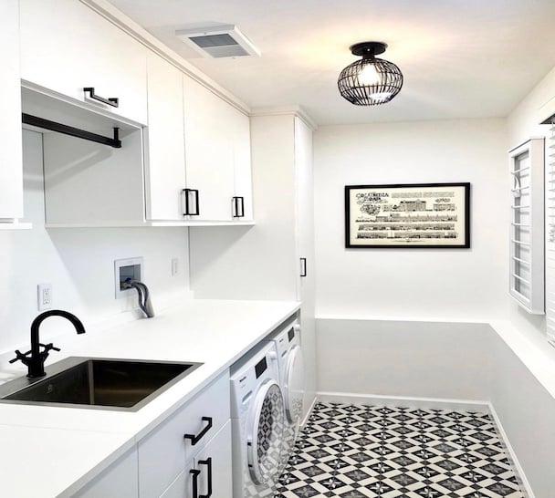 Custom laundry room with white cabinets and sink