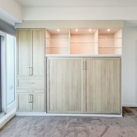Horizontal side tilt wall bed with floor to ceiling side storage, open glass shelving, and lighting.