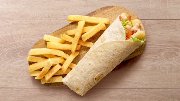 The Hake Wrap and the Calamari Wrap on a circular wooden board, both placed on a wooden surface with a green background banner.