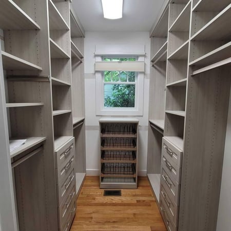 A walk-in closet featuring double-sided shelves and a window.