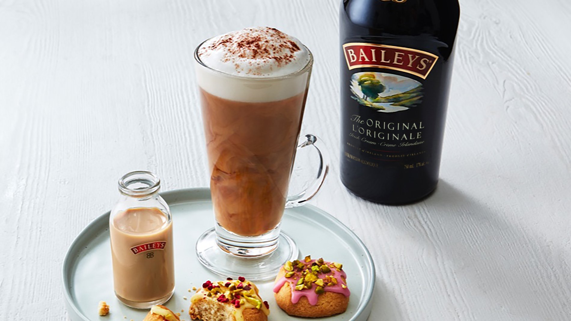 Baileys-infused latte with bottle of Baileys and small cookies