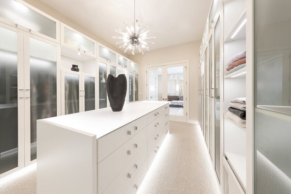 Luxurious walk-in closet with lighting, glass doors for protection, and a center island for maximum storage.