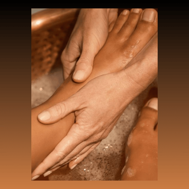 Hands on feet providing pedicure in bubbly water