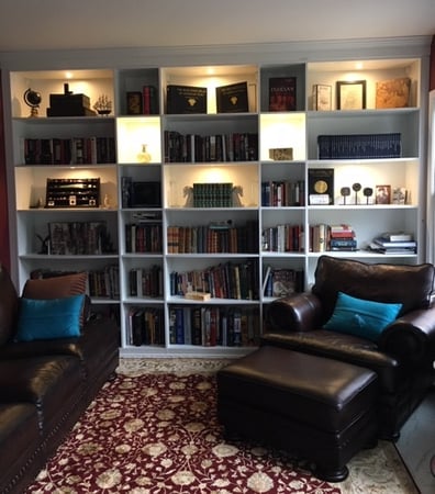 bookcases with books and lighting with leather brown furniture and floral rug