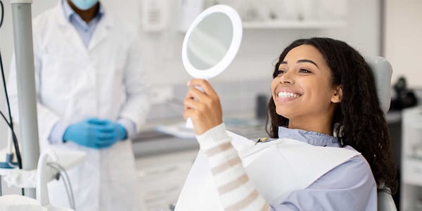 a girl smiling at a mirror in the dentist office